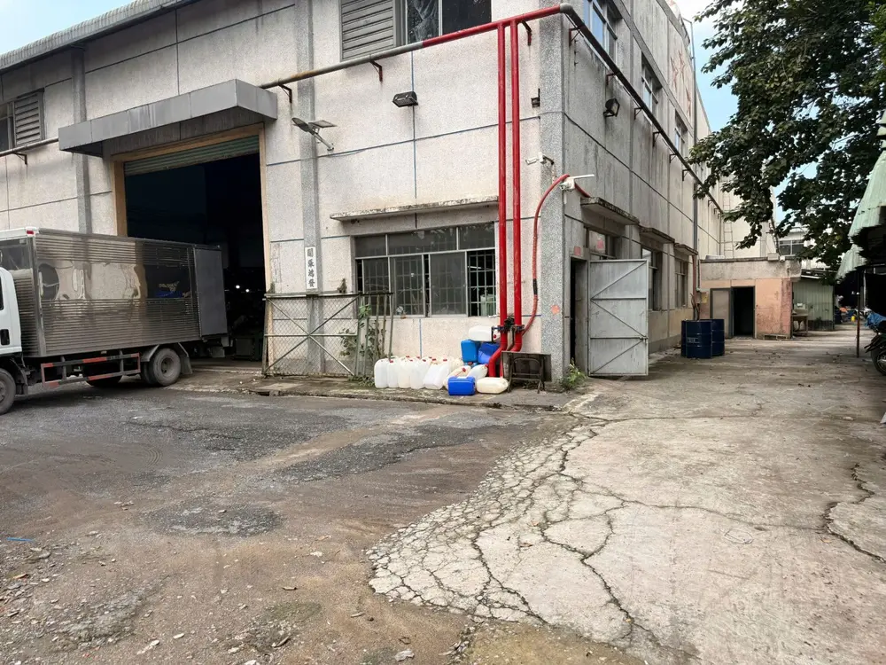 Đường ống chữa cháy sơn đỏ chạy dọc tường nhà kho, cạnh cửa cuốn và xe tải đang đỗ